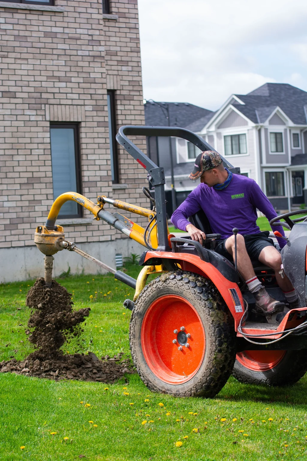 Bednarz crew operating hydraulic post hole digger for fence installation in Richmond Hill Ontario backyard