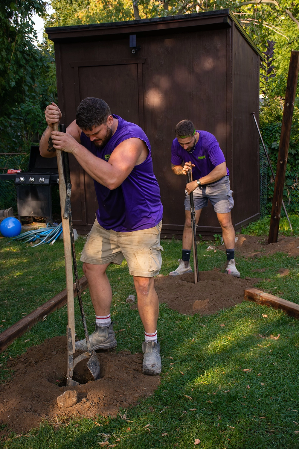 Bednarz crew members using hand tools to dig and set fence posts for residential fence installation in Port Dover Ontario yard