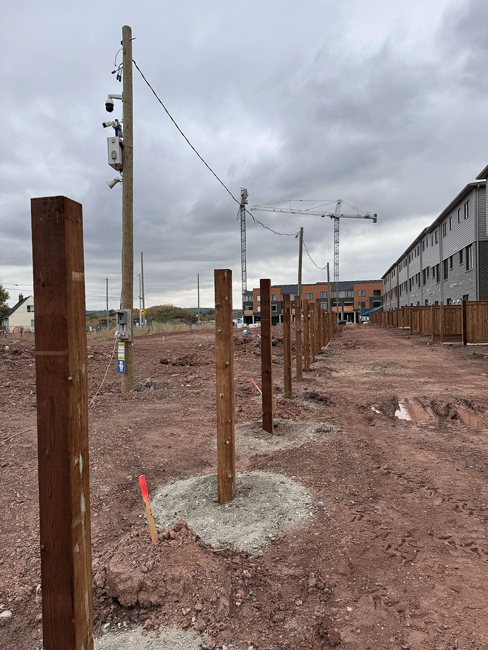 Commercial residential development with multiple wooden fence posts and deck footing installation visible in Etobicoke
