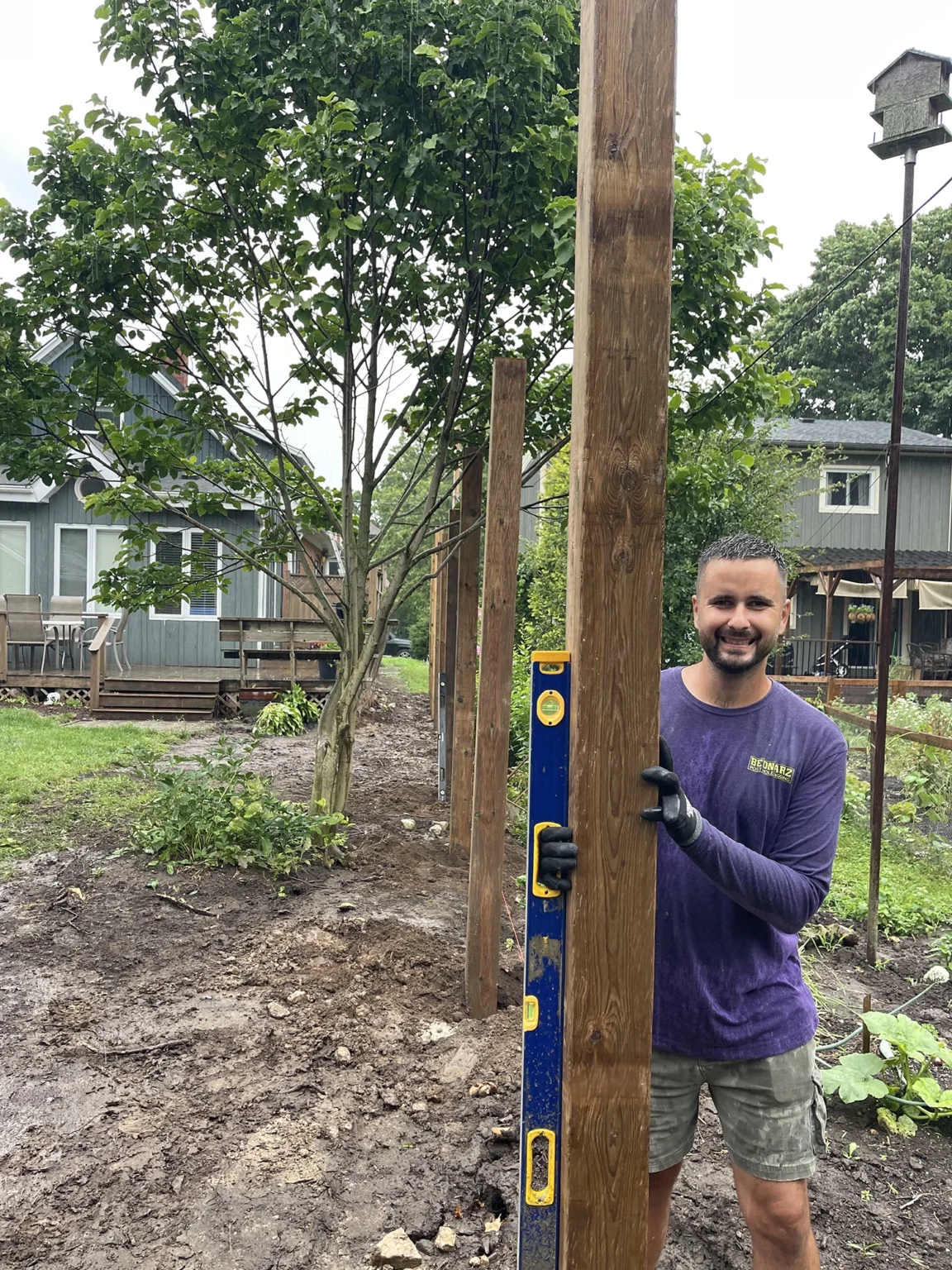 Bednarz operator holding wooden fence post for installation in residential Guelph Ontario property