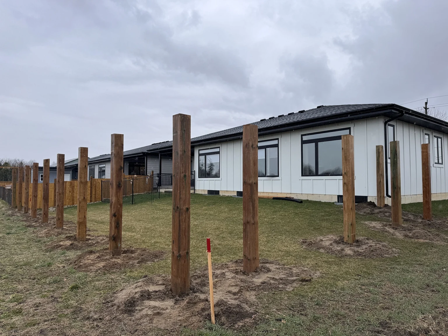 Wooden fence posts installed around residential home foundation in Fort Erie Ontario for deck project
