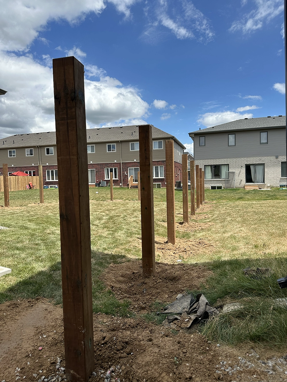 Residential fence post holes dug in Kitchener backyard showing wooden posts aligned for privacy fence installation