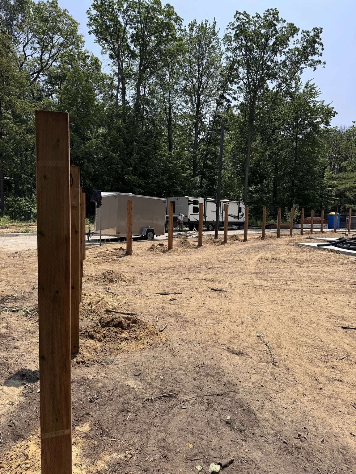 Multiple pressure-treated posts positioned for deck footing installation in Hamilton Ontario
