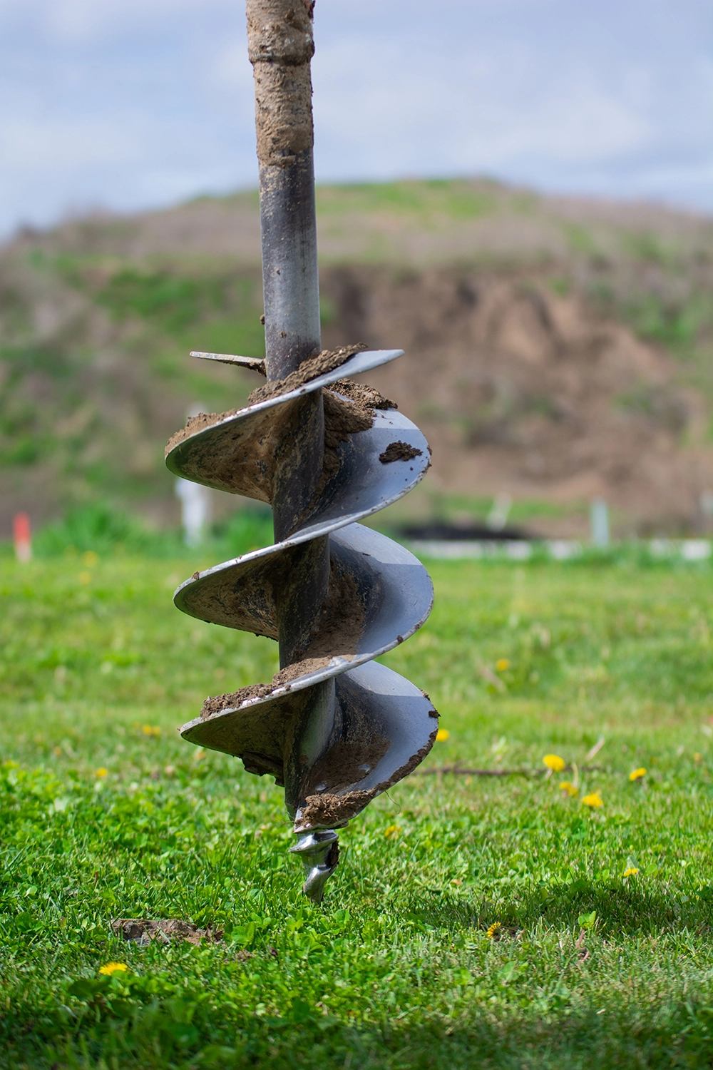 Close-up of earth auger bit showing professional post hole digging equipment used for fence installation in Niagara Falls Ontario