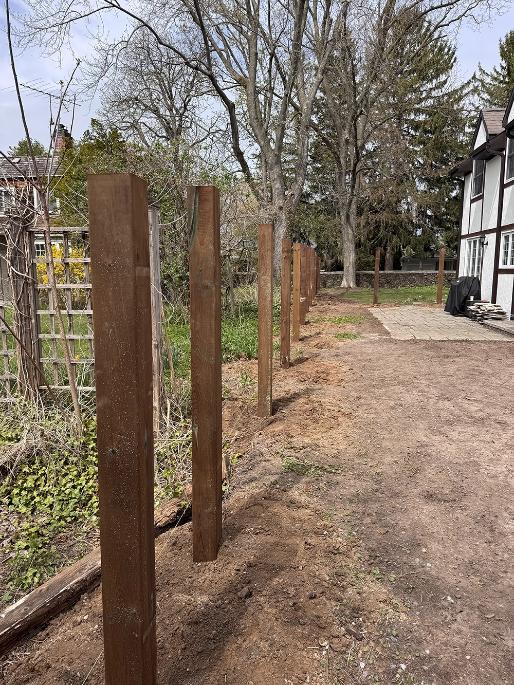 Residential fence installation in Niagara Falls Ontario with wood fence posts professionally set along driveway