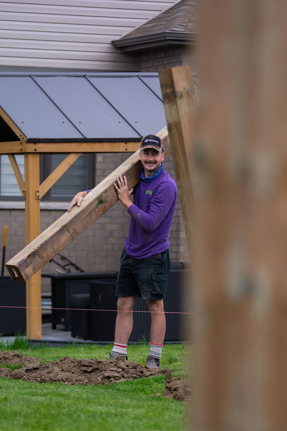Bednarz technician holding large wooden post for deck footing installation at residential property in Norfolk County Ontario