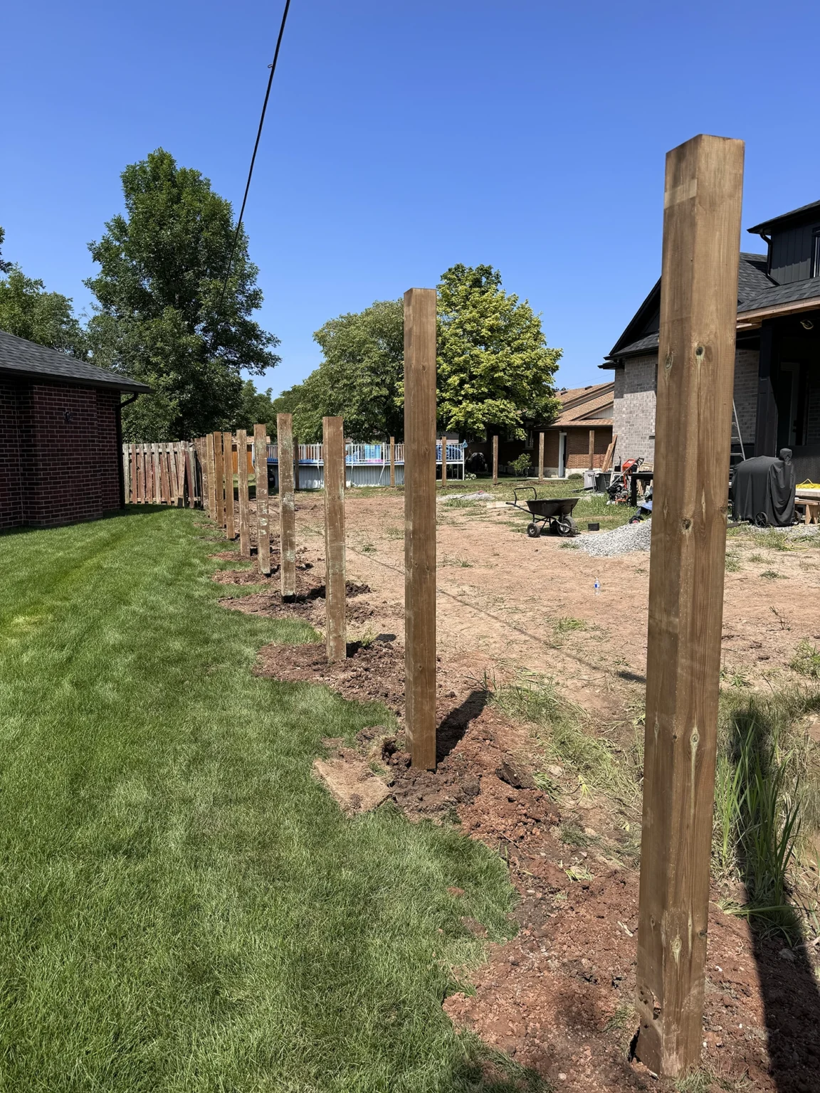 Bednarz crew installing fence posts along residential property line in Kitchener with concrete footings for deck support