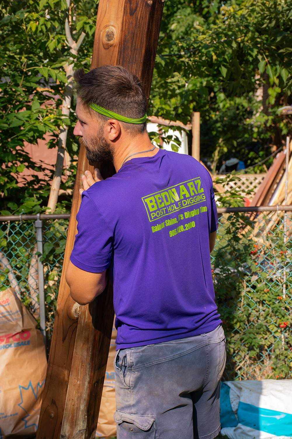 Bednarz crew member installing wooden fence post with chain link fence in Scarborough Ontario backyard
