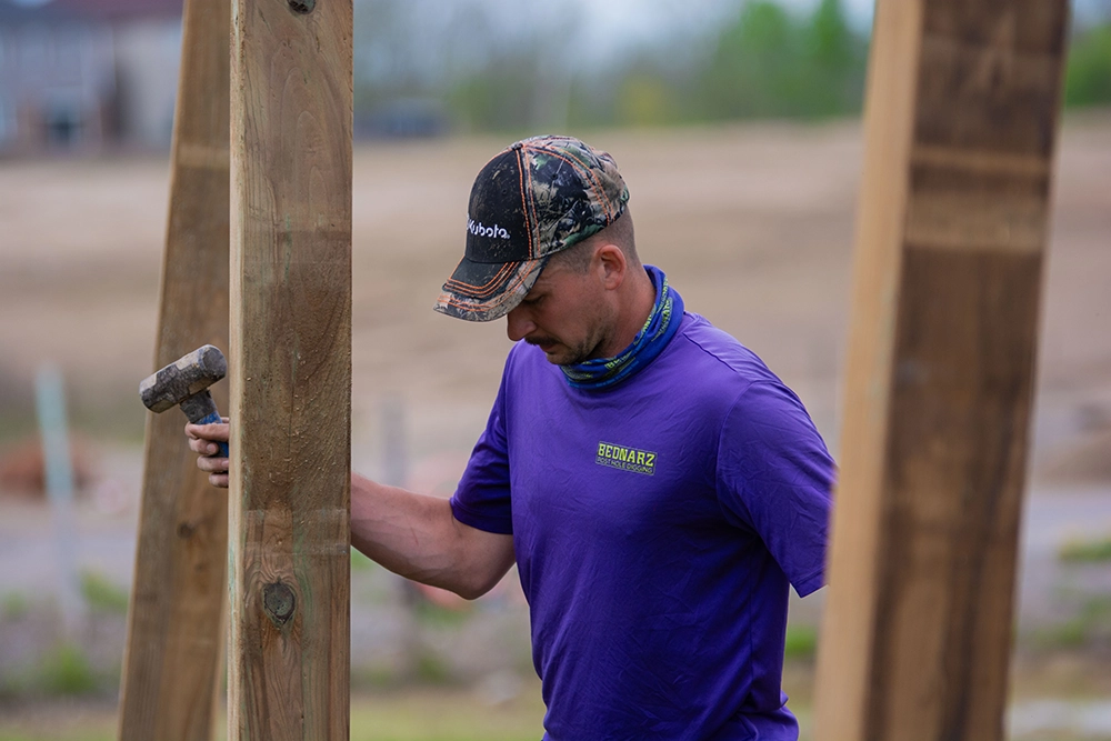 Bednarz crew member setting wooden fence post for residential fence installation in Stoney Creek Ontario