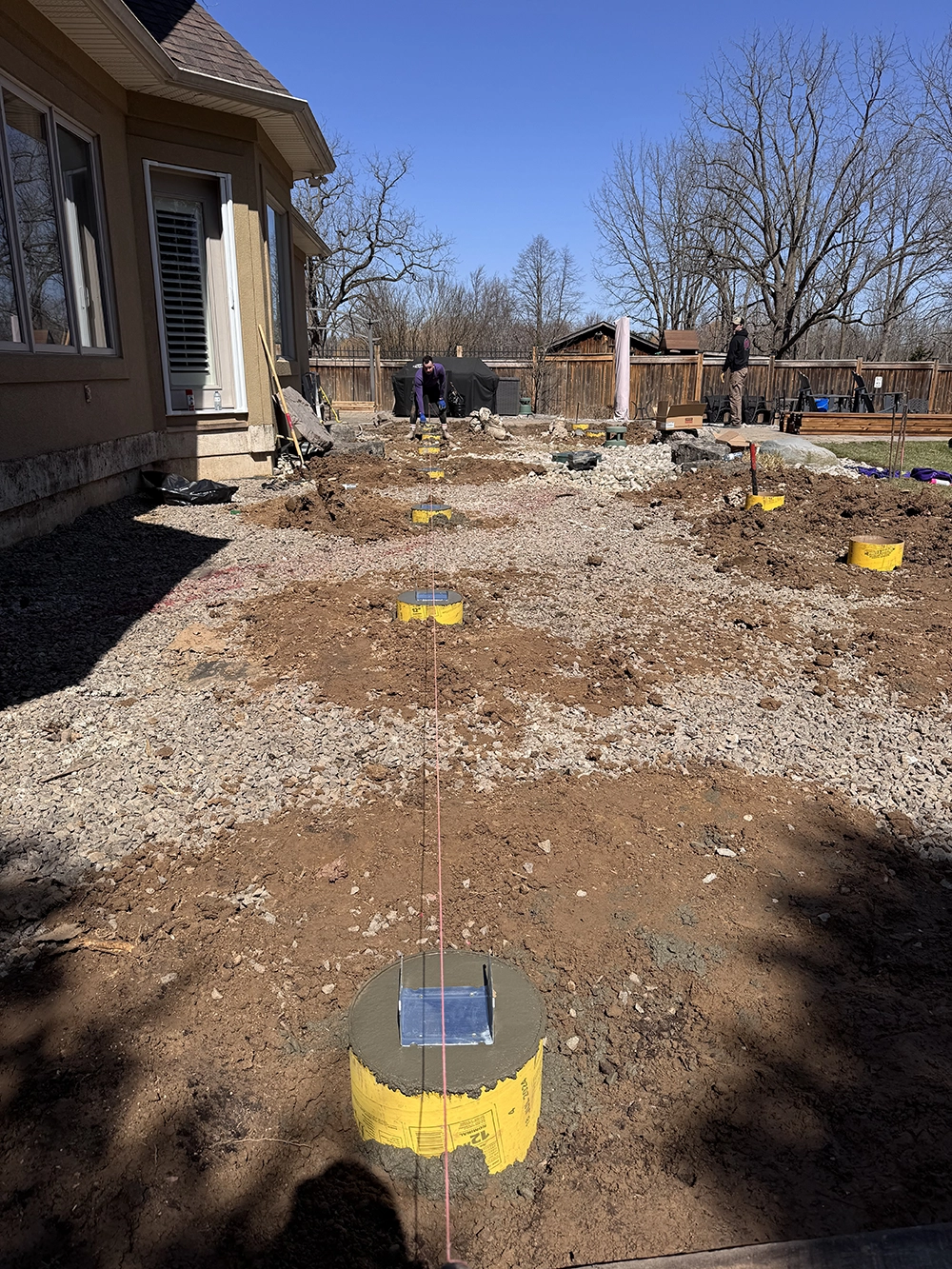 Deck footing installation with auger equipment in Woodbridge Vaughan residential yard showing professional post hole digging