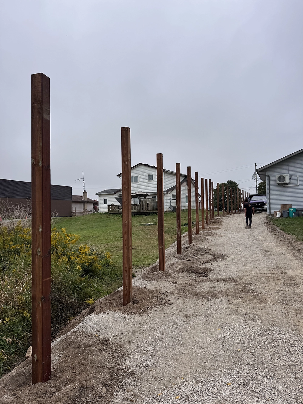 Wood fence post installation along residential driveway in Woodstock Ontario property