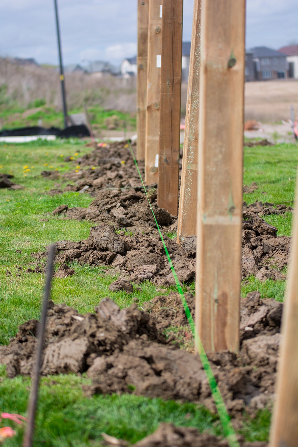 Close-up of wooden fence posts set in ground with utility marking for installation in St. Catharines