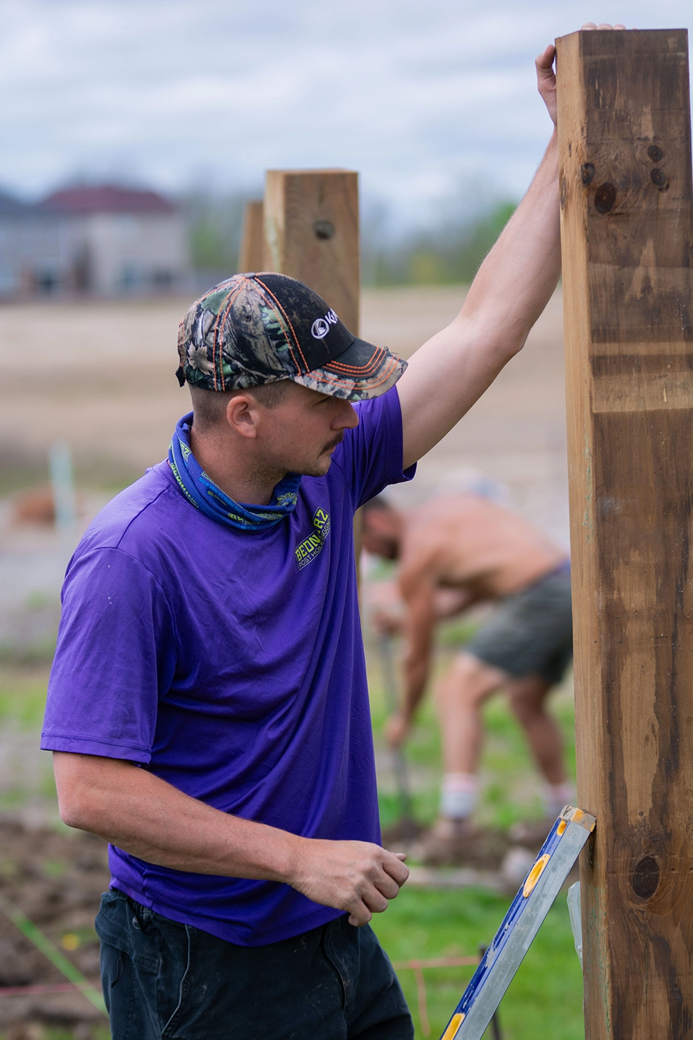 Bednarz worker measuring and leveling wooden fence post during installation in St. Catharines Ontario